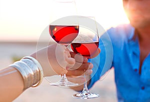 Close-up of two humanÃ¢â¬â¢s hand with wineglasses red wine during photo